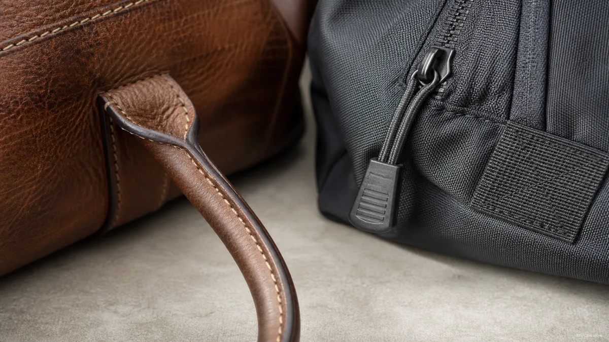 Close-up of a full-grain leather weekender's stitched handle next to a technical nylon duffle's reinforced zipper pull, no brand logos, natural daylight (AI generated illustration)