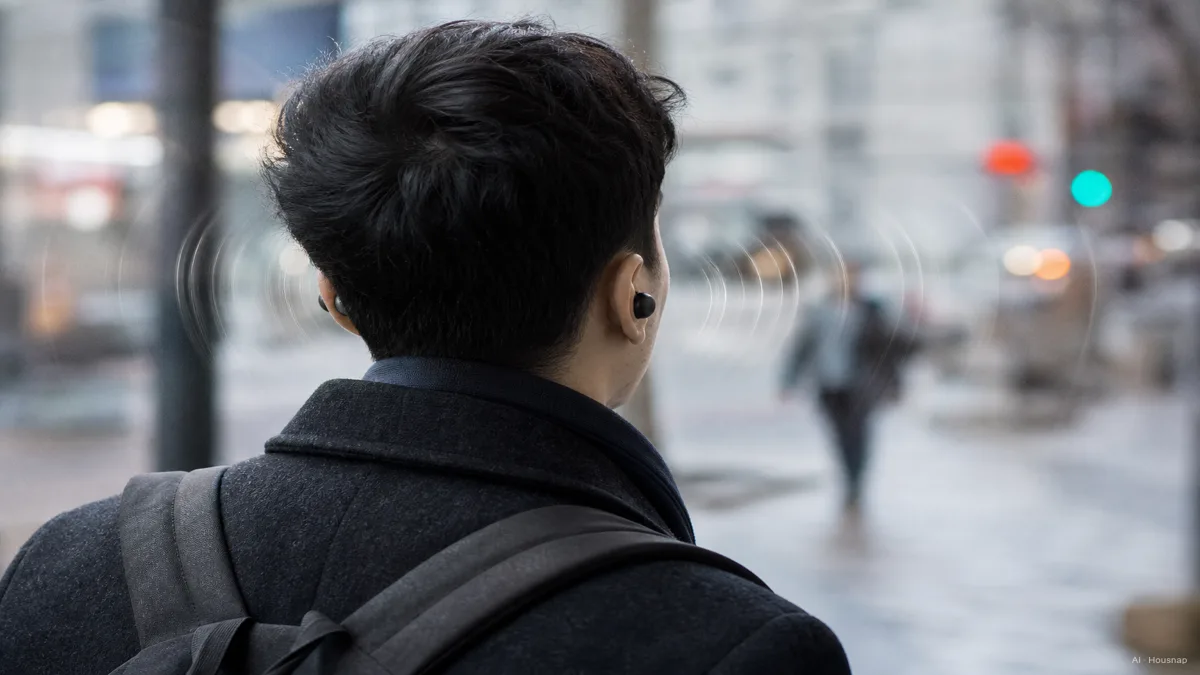 Image: a person walking a city sidewalk wearing earbuds, ambient street sounds visualized as soft waves reaching the ear — AI illustration